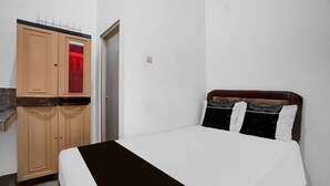 Quarto com cama, guarda-roupa e uma mesinha.