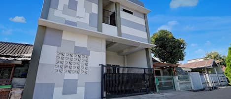 A two-story building with a modern design, featuring a balcony and a gated entrance.