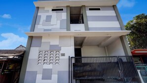 Um edifício de dois andares com design moderno, apresentando uma varanda no andar superior e uma entrada com portão.