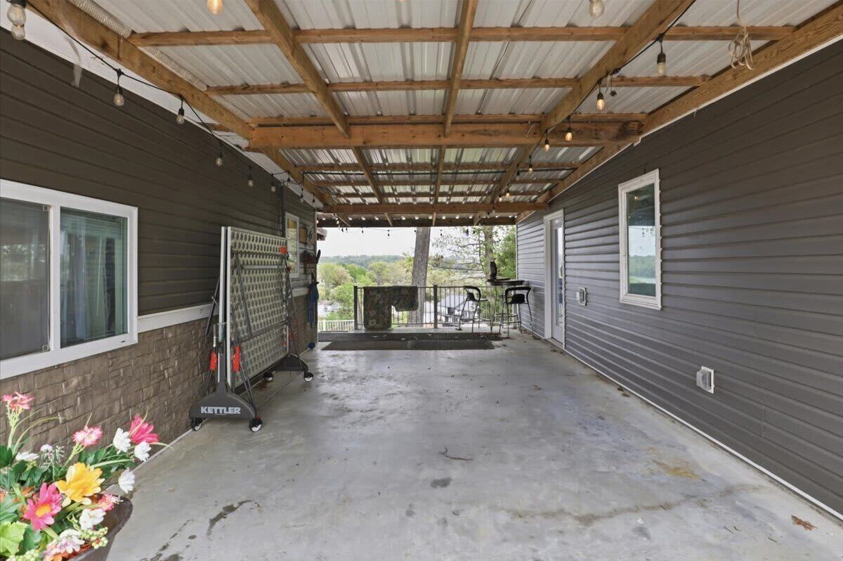 A covered outdoor area with a concrete floor, metal fencing, and a Kettler snow blower.