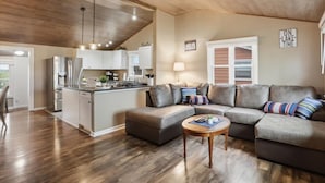 A modern kitchen with a central island, a dining area with a gray sofa and a coffee table, and a living room with a gray sectional sofa. - Perfect Lake Escape Near Bagnell Dam Strip (Lake Ozark)