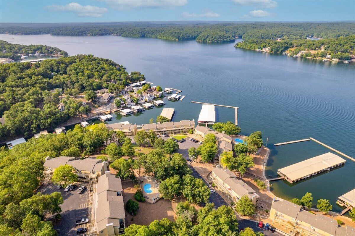 An aerial view of a lakeside property with multiple buildings, a dock, and a swimming pool.