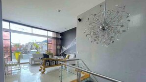 A modern interior with a staircase, a chandelier, and a view of the city. - DUPLEX ROOF CHAPINERO ALTO (Bogotá)
