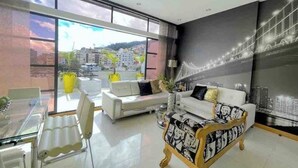 A modern living room with a glass dining table, two sofas, and a large window with a city view. - DUPLEX ROOF CHAPINERO ALTO (Bogotá)