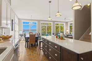 A modern kitchen with a large island, pendant lighting, and a view of the outdoors.