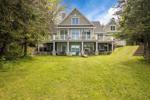 A two-story house with a covered porch, stone steps, and a grassy yard.