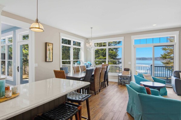 A spacious dining area with a large table and chairs, a balcony with a view, and a chandelier.