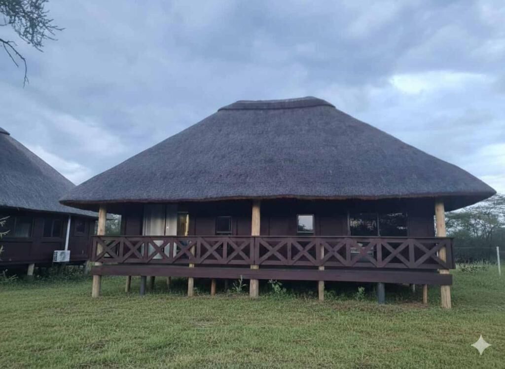 Una construcción con techo de paja y balcón de madera, rodeada de hierba.