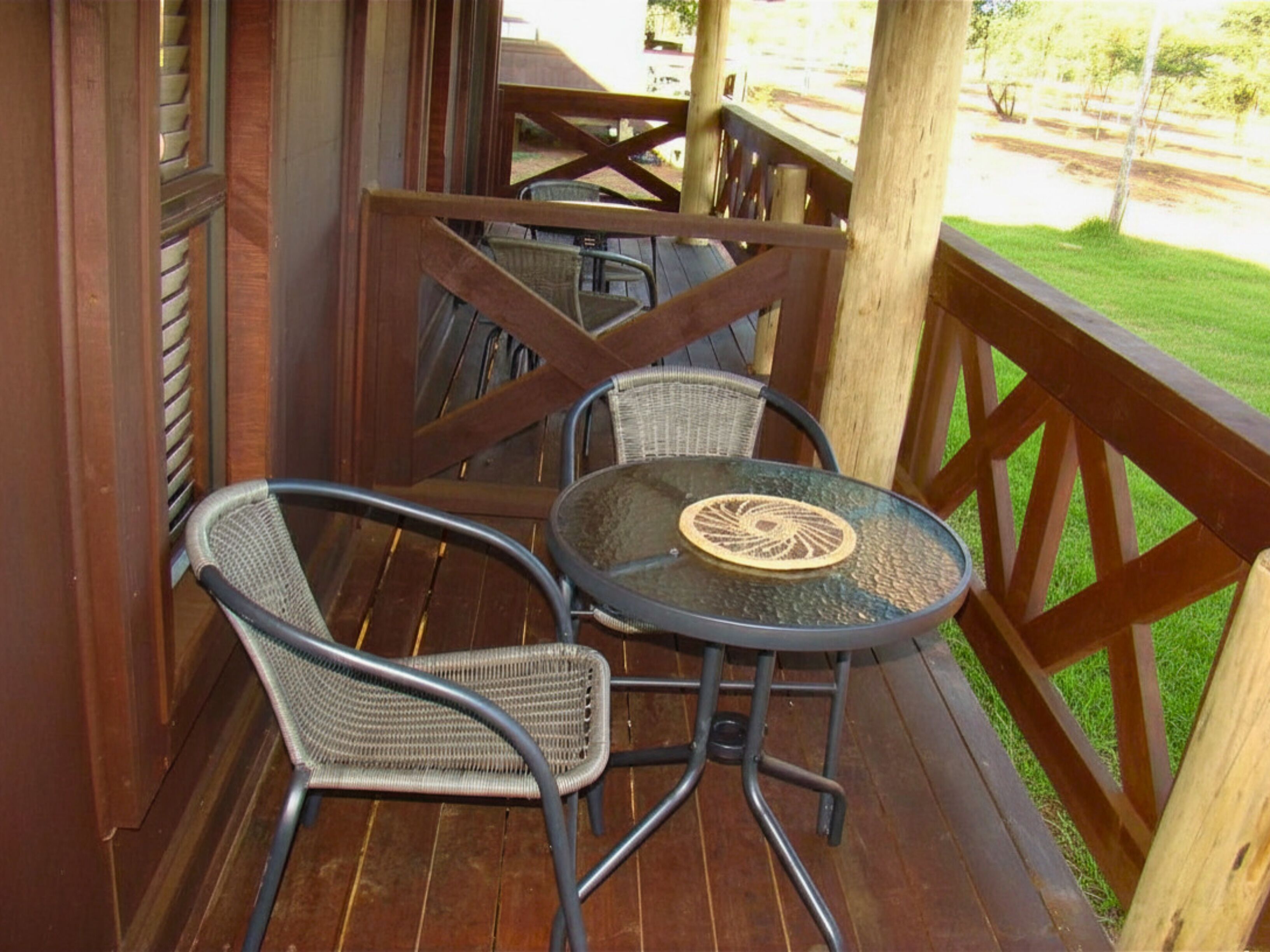A wooden deck with a round table and two wicker chairs.
