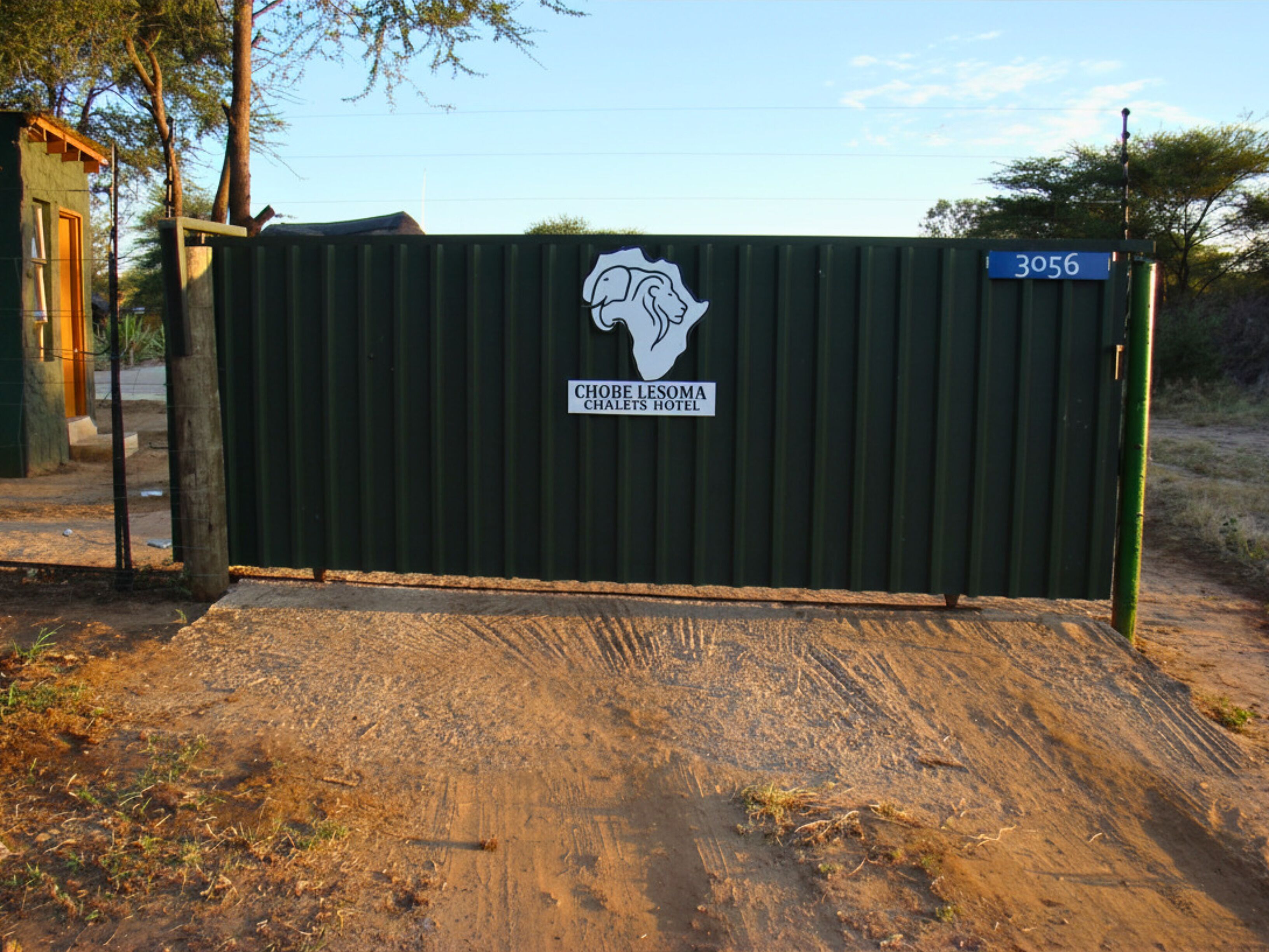 A gated entrance to Choblesoma Chalet's Hotel with a sign displaying the hotel's name and a number.