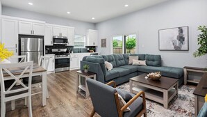 A modern kitchen with white cabinets, stainless steel appliances, and a dining area with a table and chairs. - Cozy Greenville Stay | 3 Bed, 2 Bath, Sleeps 6 (Greenville)