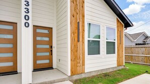 A two-story house with a garage, a front door, and a wooden accent wall. - Cozy Greenville Stay | 3 Bed, 2 Bath, Sleeps 6 (Greenville)