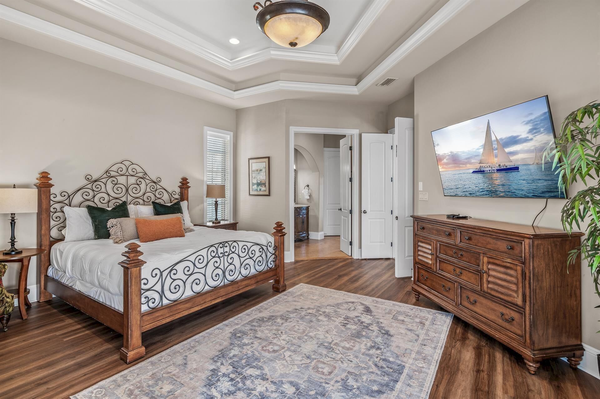 Une chambre à coucher avec un grand lit, une commode, un téléviseur et un tableau représentant un voilier.