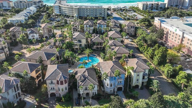 Un resort con varias edificaciones, una piscina central y vista al océano.