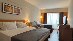 Une chambre d’hôtel avec un grand lit, un lit plus petit, un bureau et une télévision.