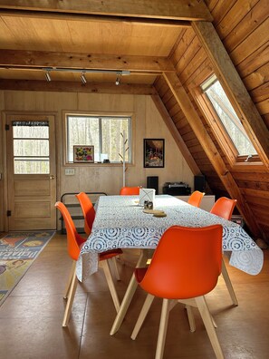Ein Essbereich mit Tisch, Stühlen und einer Decke mit Holzbalken.