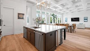 Uma cozinha espaçosa com uma ilha grande, eletrodomésticos modernos e um candelabro.