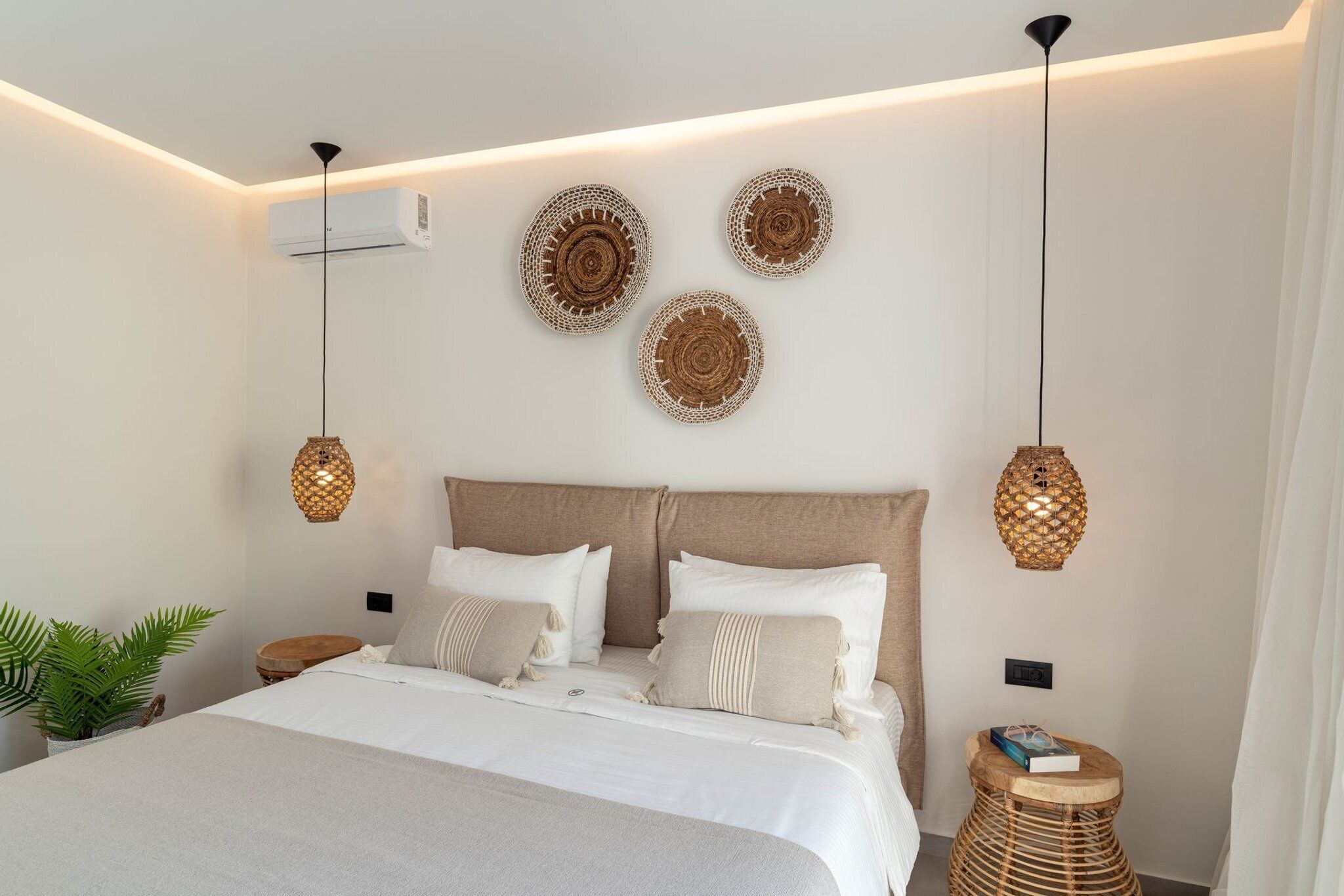 Ein modernes Schlafzimmer mit einem großen Bett, Nachttischen, einer Topfpflanze und Wanddekoration.