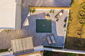 Vue aérienne d’un toit-terrasse avec une piscine rectangulaire, des chaises longues et des plantes en pot.