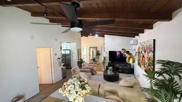 A modern living room with a sofa, TV, and artwork.
