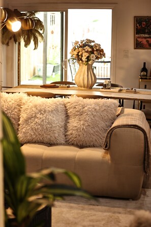 A living room with a sofa, a vase with flowers, and a dining table. - City escape near beach sunsets & LA adventures (Los Angeles)