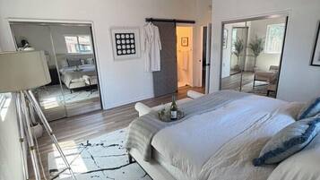 A bedroom with a large bed, a mirror, a bedside table, and a wardrobe.