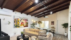 Un soggiorno ampio con soffitto alto, un divano, due poltrone, un tavolino da caffè e una televisione.