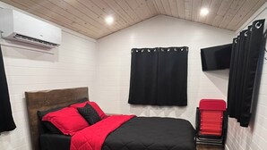 A bedroom with a bed, a chair, a desk, and an air conditioning unit. - Otter's Edge Estates (Vienna)
