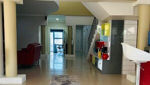 Un pasillo amplio con un tapete central, una escalera y una zona de cocina con armarios y un lavabo.