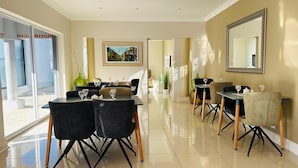 Un comedor moderno con una mesa larga, sillas y un espejo grande en la pared.