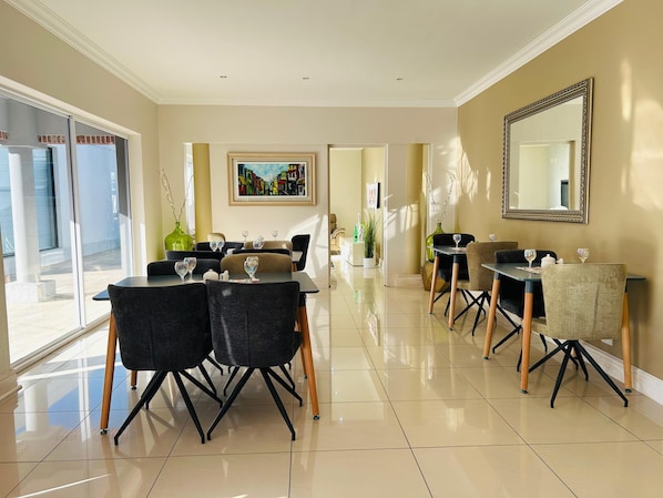 A modern dining area with a long table, chairs, and a large mirror on the wall. - 50 Boutique Hotel and Spa (Port Elizabeth)
