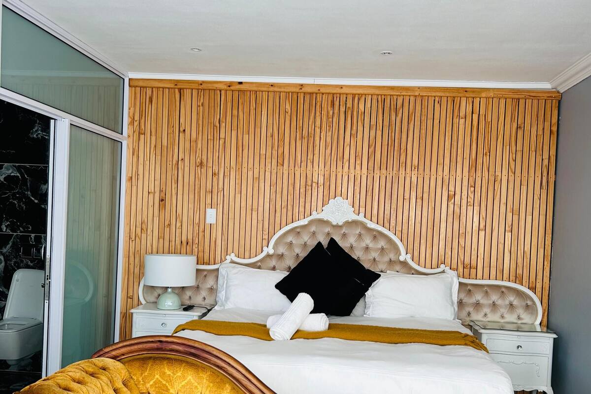 Une chambre à coucher avec un grand lit, une tête de lit en bois, une table de chevet et une commode.