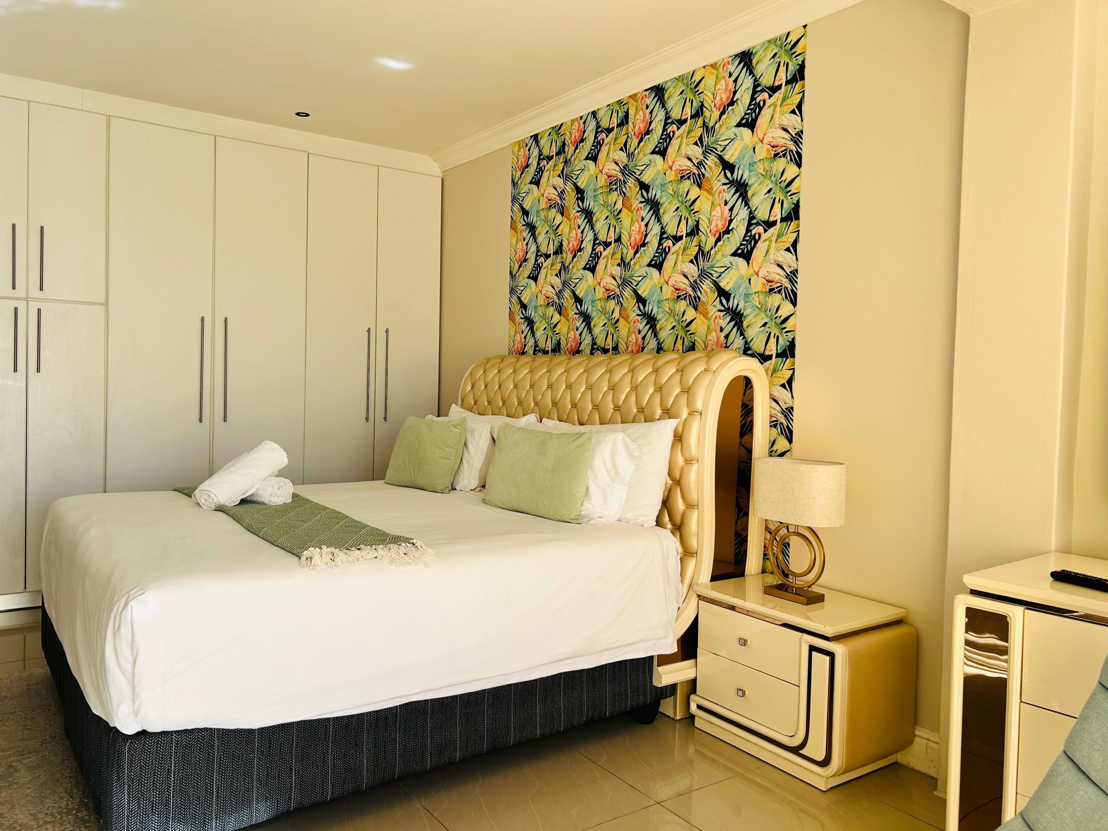 Quarto com cama, mesa de cabeceira, abajur e guarda-roupa.