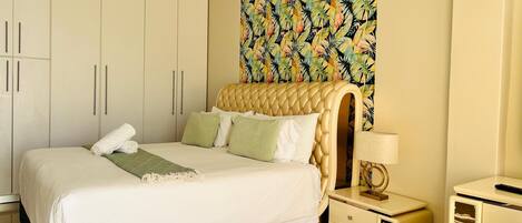 A bedroom with a bed, a nightstand, a lamp, and a wardrobe.