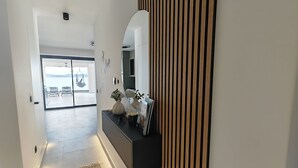 Un pasillo de diseño moderno, un consola negra con objetos decorativos, un espejo grande y vistas al exterior.