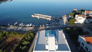 Vista aérea de un puerto deportivo con barcos amarrados, una piscina y edificios con techos de tejas rojas.