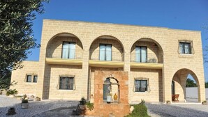 Un bâtiment doté d’une façade en pierre, de plusieurs arcades et d’une cour intérieure agrémentée de plantes en pot.