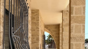 Un couloir aux murs de pierre, doté d’une grille métallique et d’un sol carrelé.