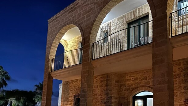 Un bâtiment doté d’une façade en pierre, de balcons en arc de cercle et d’une cour dallée.