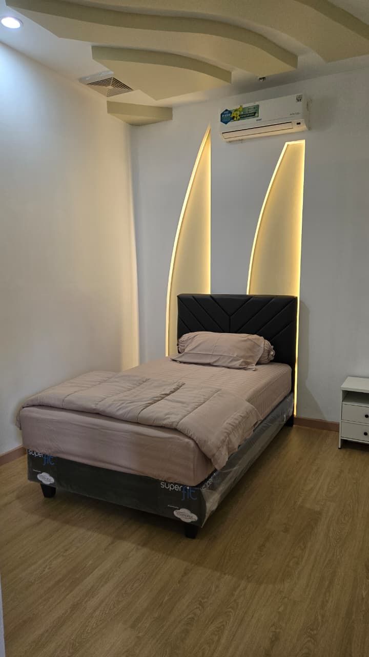 Un dormitorio con una cama, una mesita de noche y un equipo de aire acondicionado en la pared.