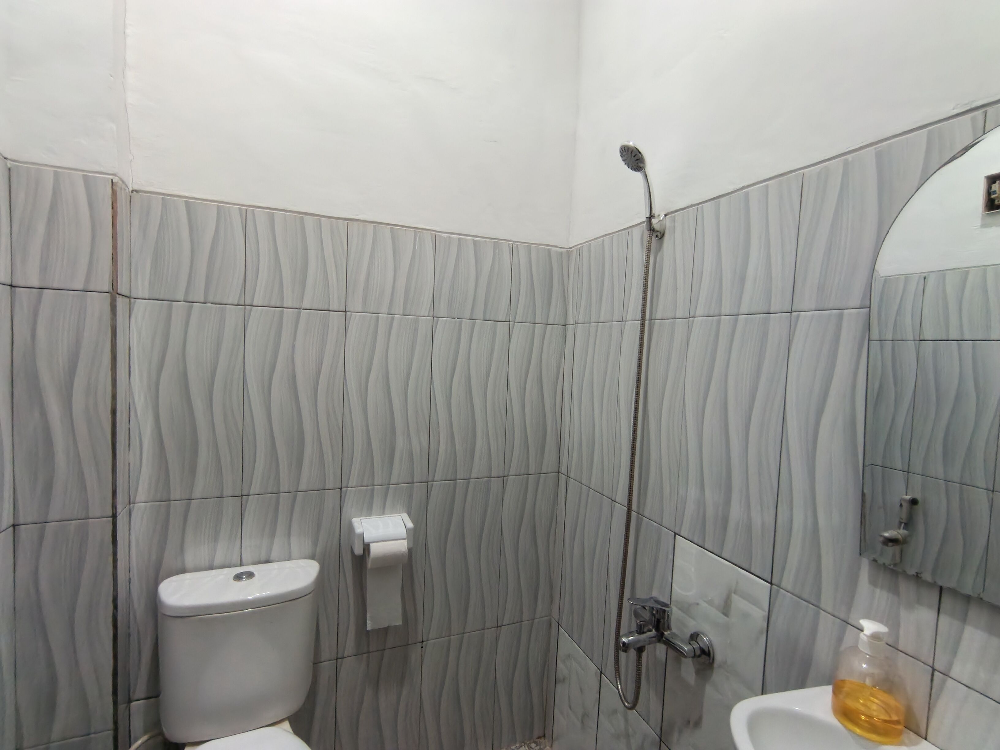 A bathroom with a toilet, a shower, and a sink.