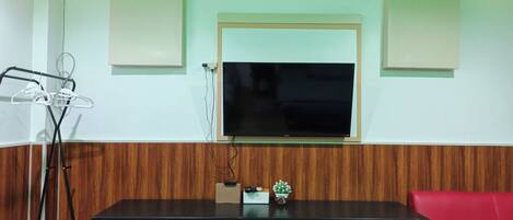 Una habitación con un televisor montado en la pared, un armario rojo, un sofá rojo y una pared de paneles de madera.