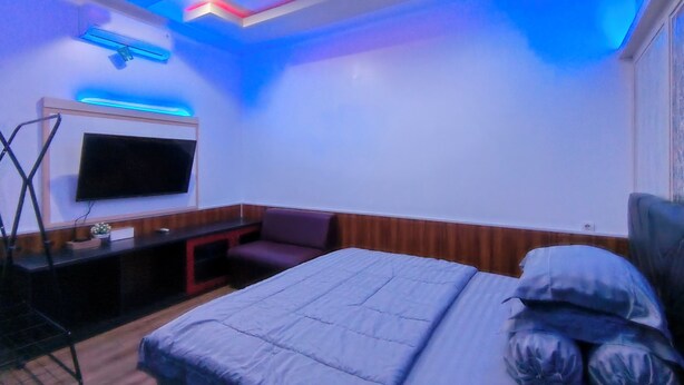 A bedroom with a bed, a TV mounted on the wall, and a desk with a chair.