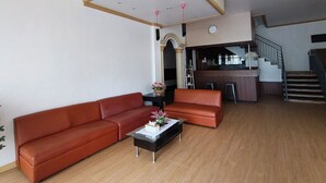 A modern living room with a sofa, a coffee table, and a staircase leading to a kitchen area.