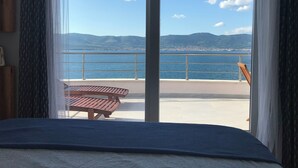 A room with a large sliding glass door leading to an outdoor balcony with a view of the sea and mountains. - Blissful apartment by the sea with panoramic view (Slatine)