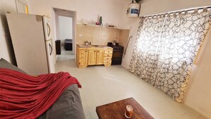 A compact living space with a kitchenette, a dining area, and a shower curtain with a geometric pattern.