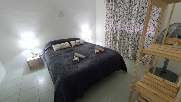 A neatly made bed with pillows, a bedside lamp, and a wooden chair.