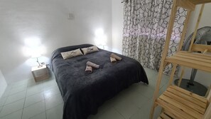 A neatly made bed with pillows, a bedside lamp, and a wooden chair.