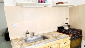A kitchen with a stone countertop, wooden cabinets, a stove, and a sink.