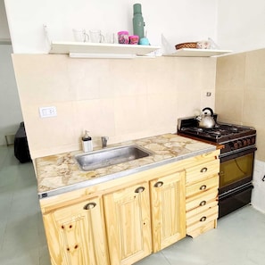 Une cuisine dotée d’un plan de travail en pierre, de meubles de rangement en bois, d’une cuisinière et d’un évier.
